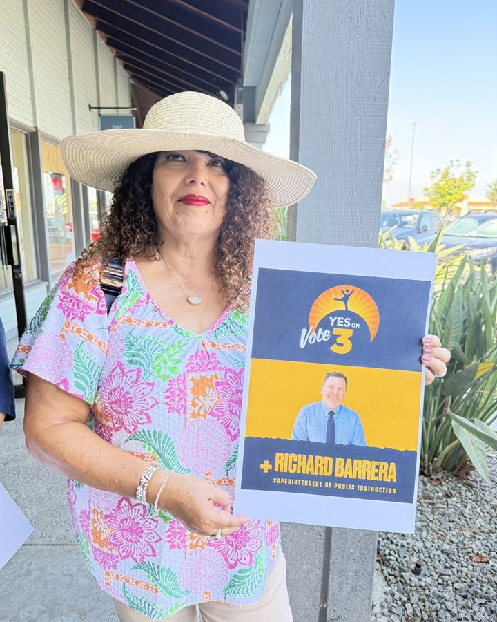 Zenaida Rosario holding a Yes on Prop 3 and Richard Barrera sign